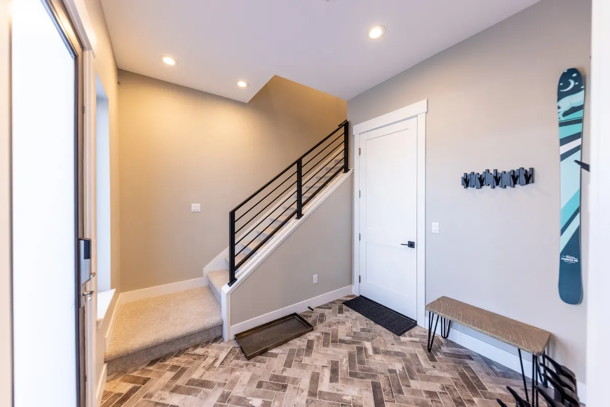 A welcoming mudroom area featuring a wooden bench, ski-themed decor on the wall, and practical flooring. The setting captures the transitional zone between outdoor adventure and indoor comfort, ideal for removing boots or stowing winter gear.