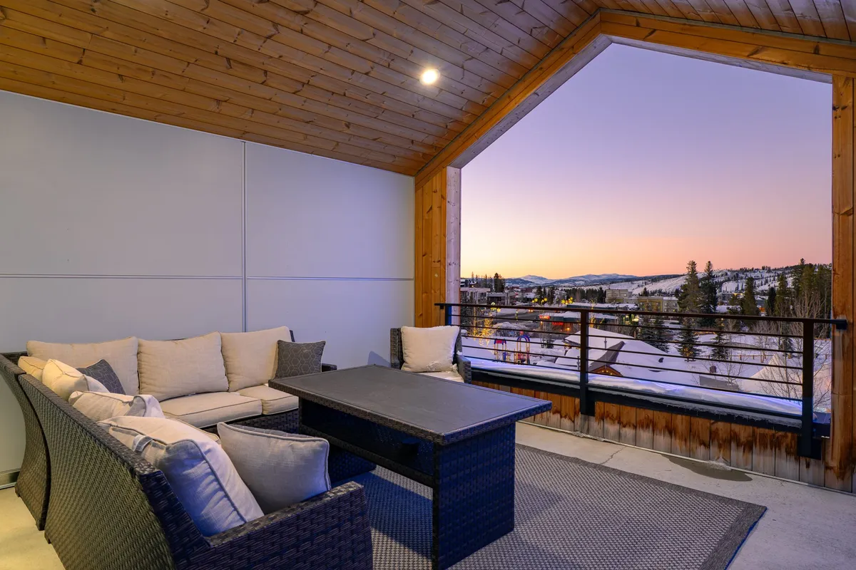 An outdoor seating area overlooking a mountain view with a sunset sky, inviting guests to relax and socialize while enjoying the natural beauty. The space feels warm and communal, ideal for multi-generational gatherings and shared moments.